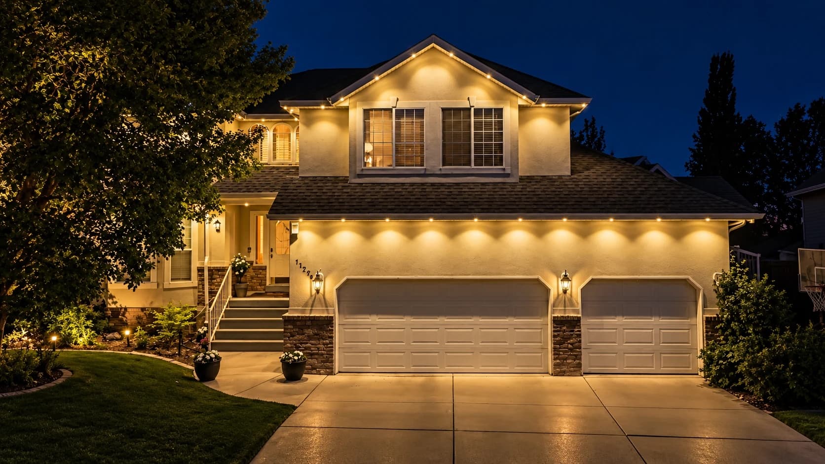 Stucco home at dusk with evenly spaced permanent lights washing warm light down the walls